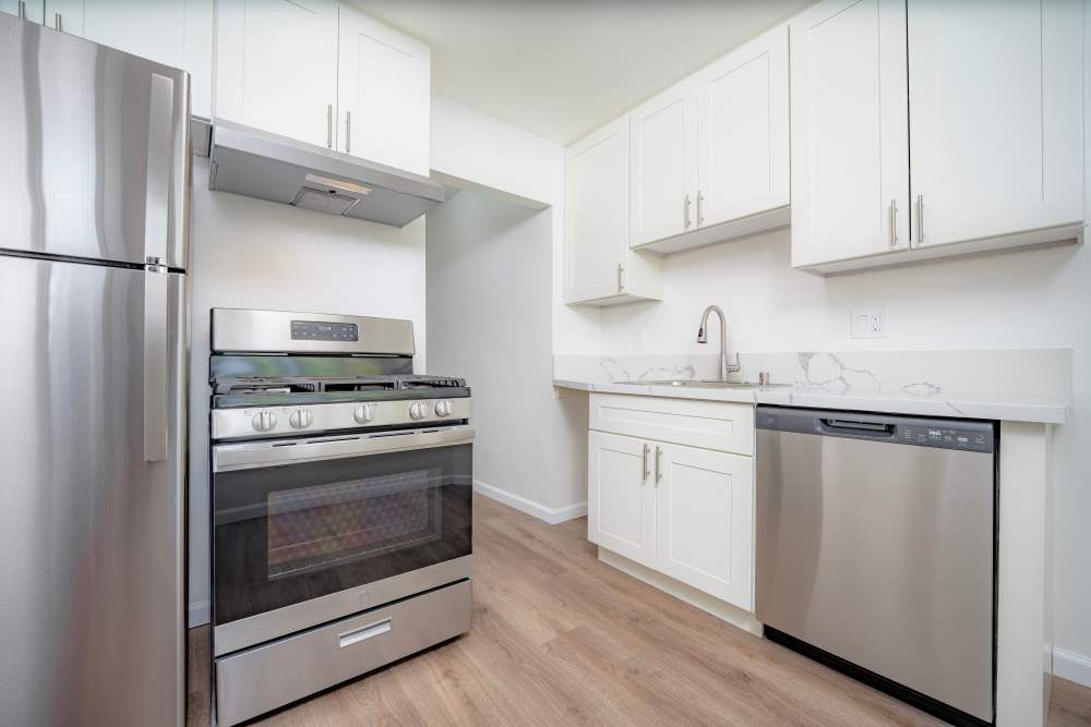 Sleek kitchen featuring stainless steel appliances, including a refrigerator and gas stove, with white cabinetry and countertops, at Copa Cabanas in Santa Cruz, California.