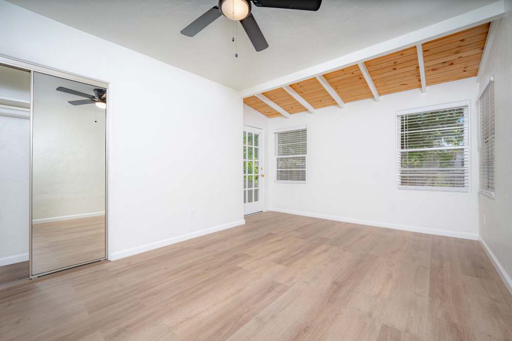 Spacious room with high ceilings, a ceiling fan, and mirrored closet doors, featuring light-colored walls and flooring, at Copa Cabanas in Santa Cruz, California