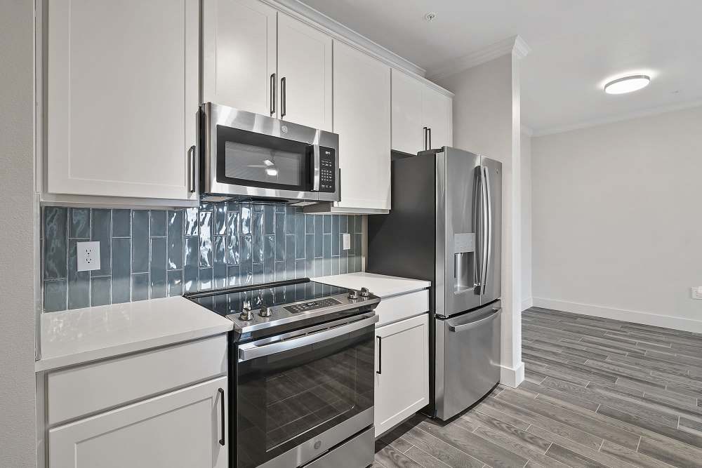 Apartment kitchen with wood-style flooring and white cabinetry at Vineyards in Katy,Texas
