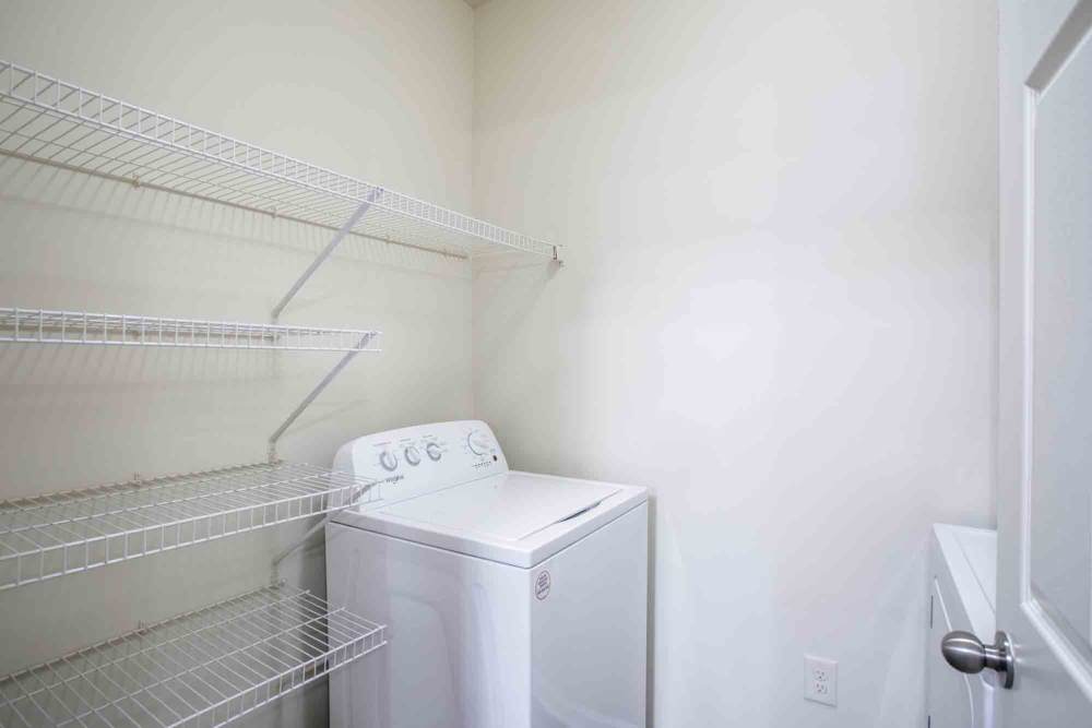 Small laundry room with white washing machine and wire shelving at Commonwealth at 31 in Spring Hill, Tennessee.