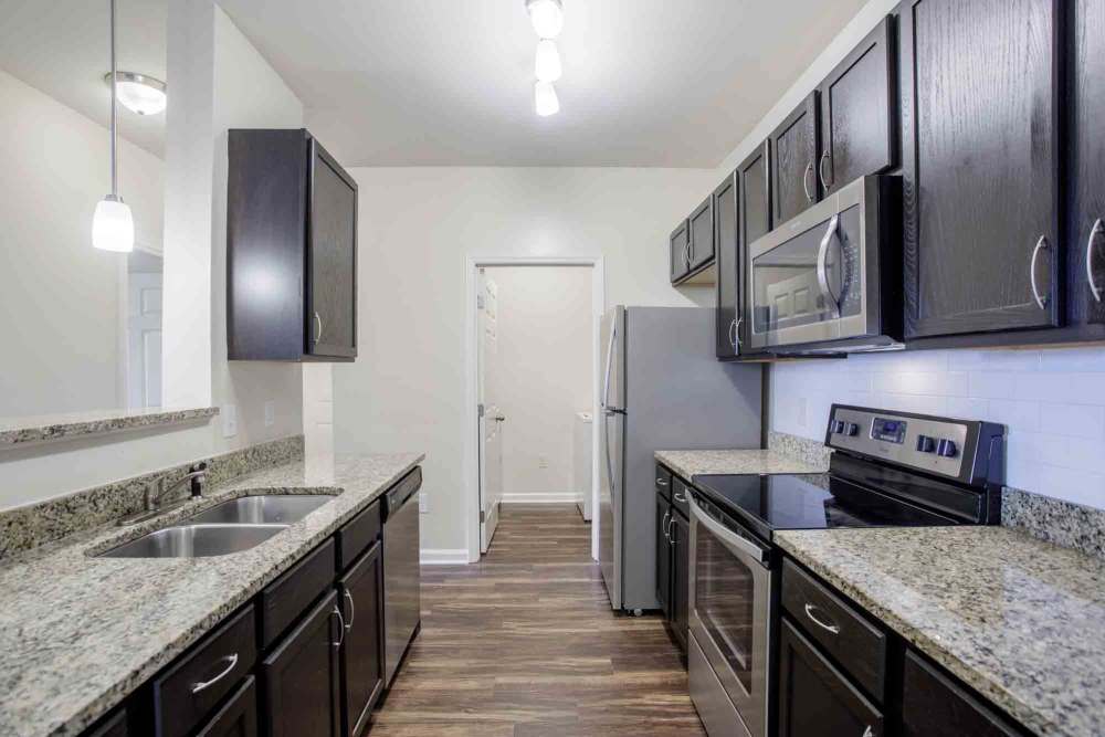 Modern kitchen with dark cabinets, granite countertops, and stainless steel appliances at Commonwealth at 31 in Spring Hill, Tennessee.
