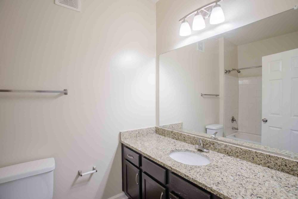 Bathroom with granite countertop, dark cabinets, and a bathtub/shower combo at Commonwealth at 31 in Spring Hill, Tennessee.