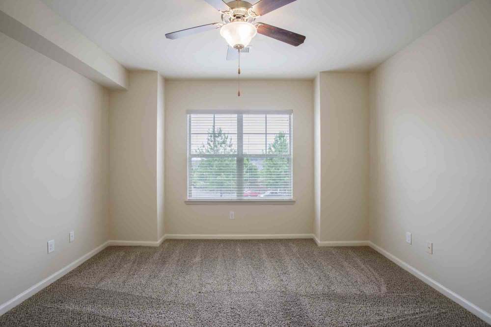 Empty room with beige walls, carpeted floor, ceiling fan, and large window at Commonwealth at 31 in Spring Hill, Tennessee.