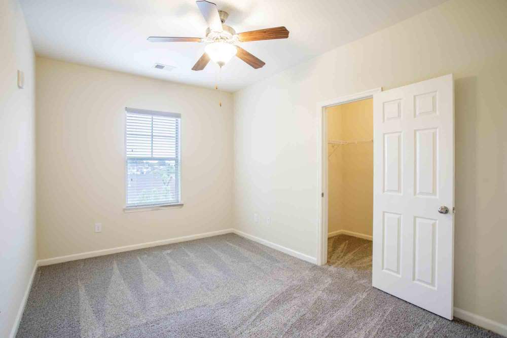 Empty room with beige walls, gray carpet, ceiling fan, and closet at Commonwealth at 31 in Spring Hill, Tennessee.