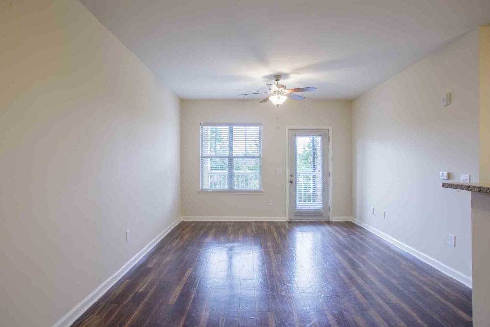 Empty room with wood flooring, ceiling fan, and access to balcony at Commonwealth at 31 in Spring Hill, Tennessee.