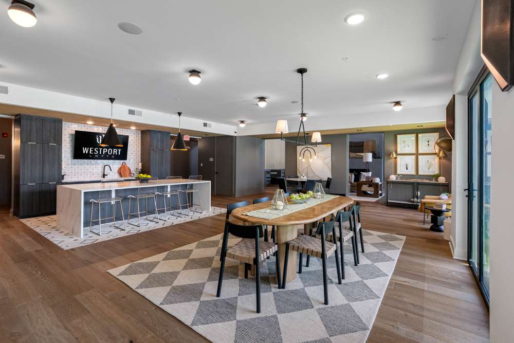 Open-concept kitchen and dining area with large island, pendant lighting, and wooden dining table at Westport Lofts in Belville, North Carolina.