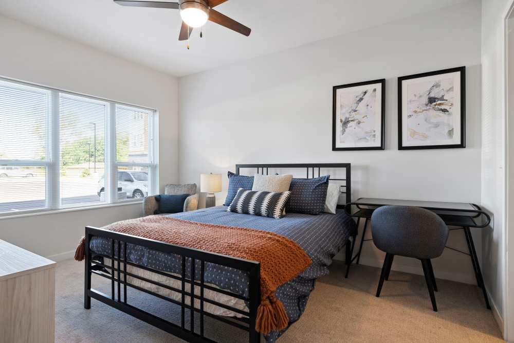Well-lit bedroom with a comfortable bed and a ceiling fan at Axle Apartments in Fridley, Minnesota