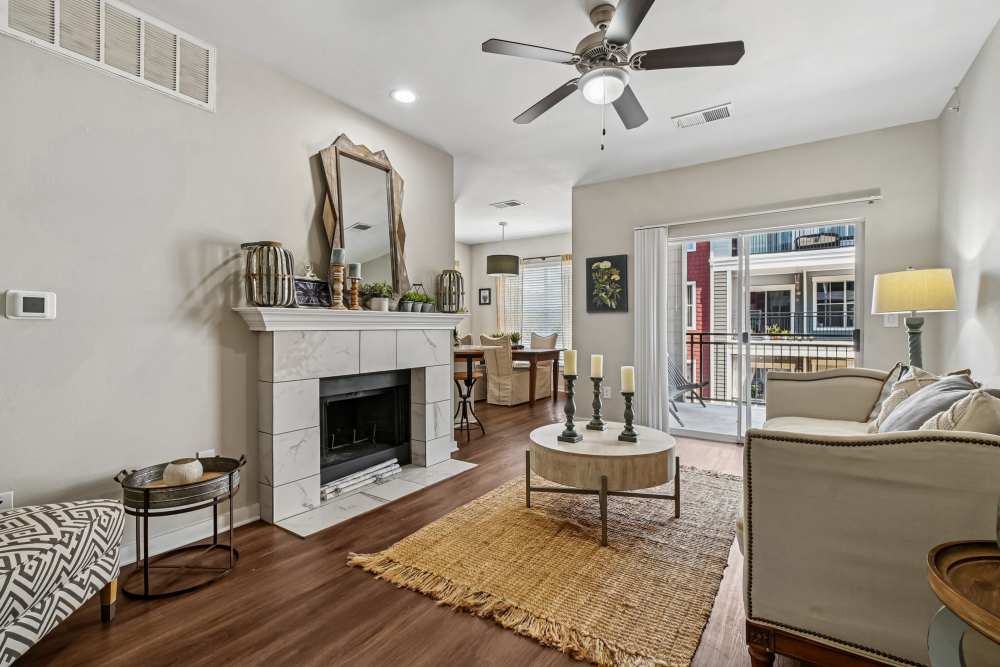 A warm living room featuring a fireplace and a plush couch at Flatiron District at Austin Ranch in The Colony, Texas