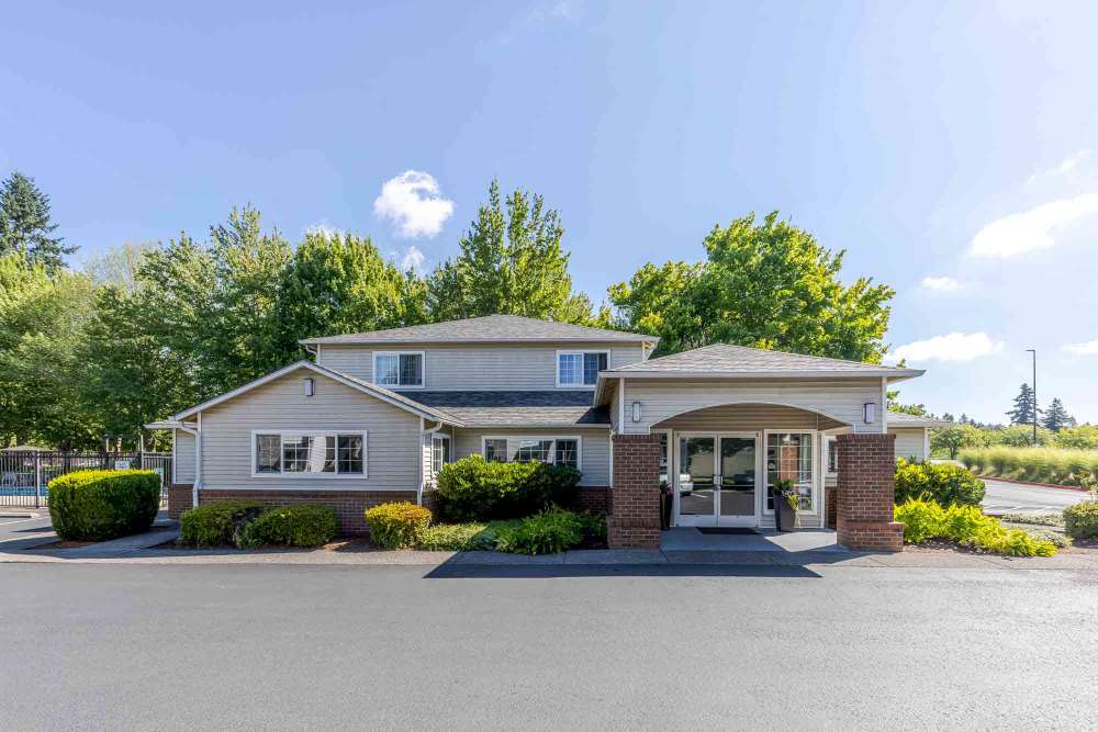 Two-story brick and siding building with trees and blue sky at Marketplace Apartments in Vancouver, WA