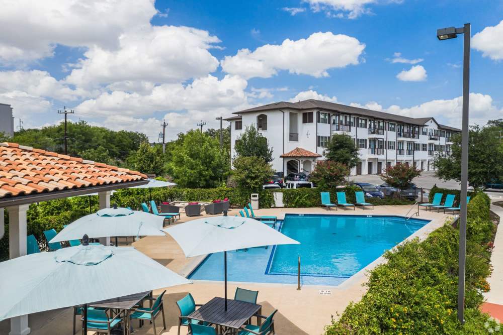 Inviting pool area with chic umbrellas and comfortable lounge seating at Alcove at Alamo Heights in San Antonio, Texas