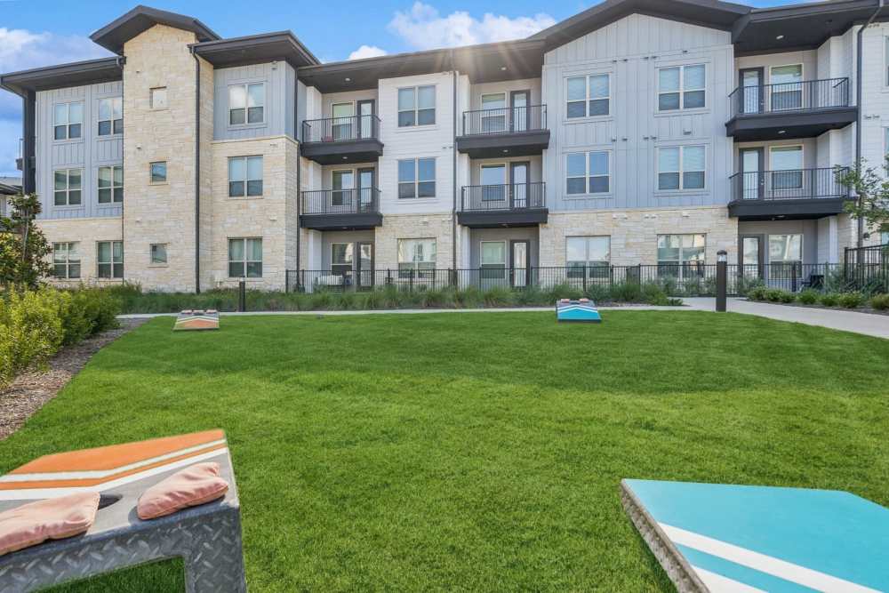 Exterior view of apartment with cornhole game at The Springs at Georgetown in Georgetown, Texas