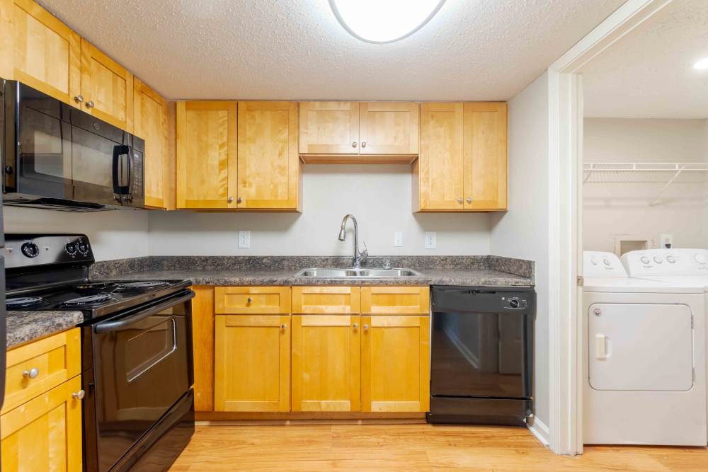A kitchen featuring a washer and dryer, a refrigerator, and a stove, showcasing essential appliances for home cooking and laundry at 865 Bellevue Apartments in Nashville, Tennessee