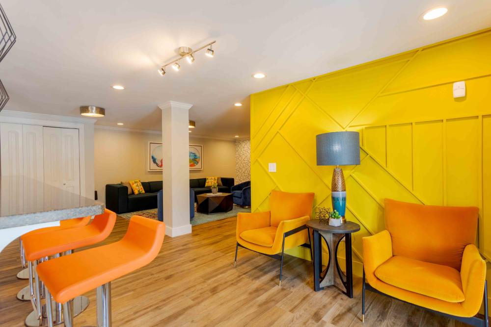 A bright yellow living room featuring vibrant orange chairs, creating a cheerful and inviting atmosphere at 865 Bellevue Apartments in Nashville, Tennessee