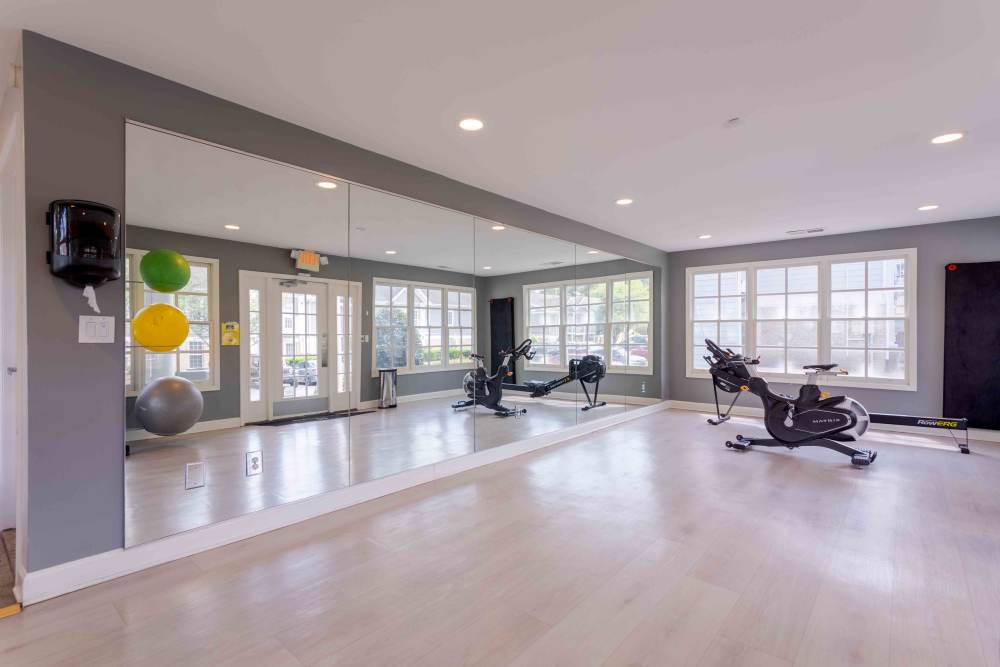 A gym room featuring mirrors and various exercise equipment arranged for workouts at 865 Bellevue Apartments in Nashville, Tennessee