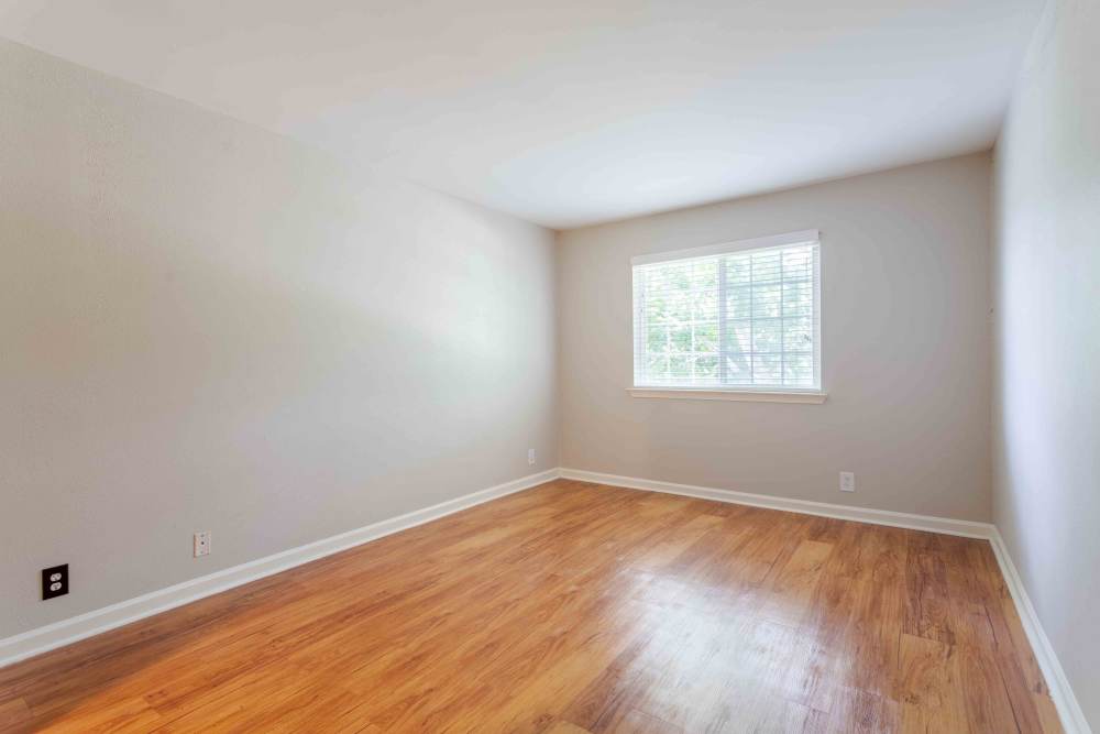 Spacious empty room with polished hardwood floors and a window, creating a bright and airy atmosphere at 865 Bellevue Apartments in Nashville, Tennessee