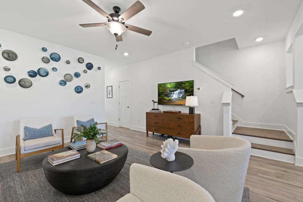Modern living room with light furniture, wall art, and a mounted TV at Artisan Living Mills River in Mills River, North Carolina