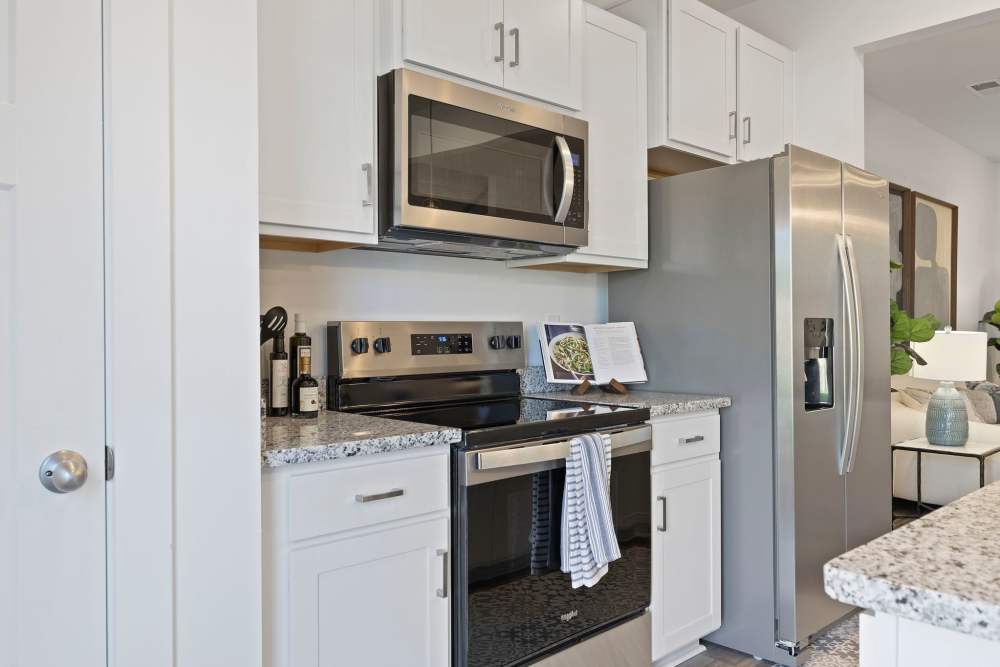 Modern kitchen with white cabinets, granite countertops, and stainless steel appliances at Artisan Living Mills River in Mills River, North Carolina