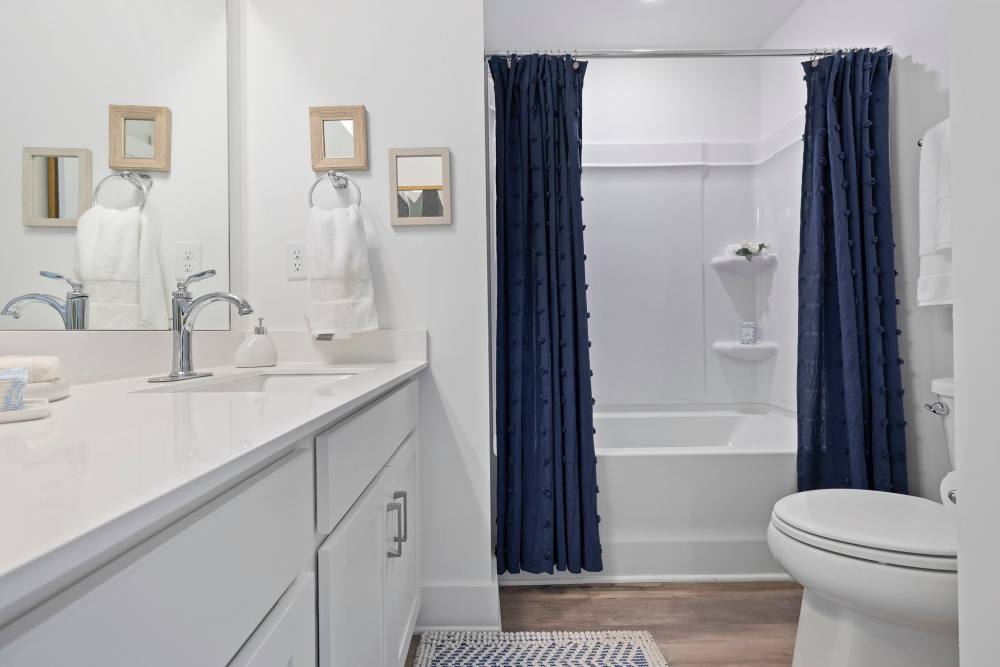 Modern bathroom with white sink and blue shower curtains at Artisan Living Mills River in Mills River, North Carolina