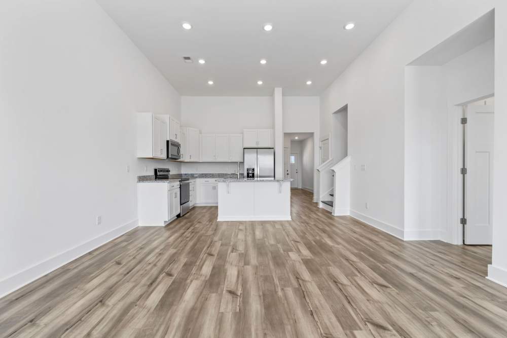 Open kitchen and living area with granite island, stainless steel appliances, and wood flooring at Artisan Living Mills River in Mills River, North Carolina
