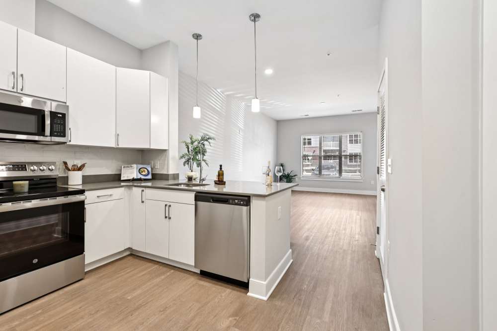 Bright white kitchen with stainless steel appliances, quartz countertops, and wood flooring, Elms Shady Grove in Rockville, Maryland