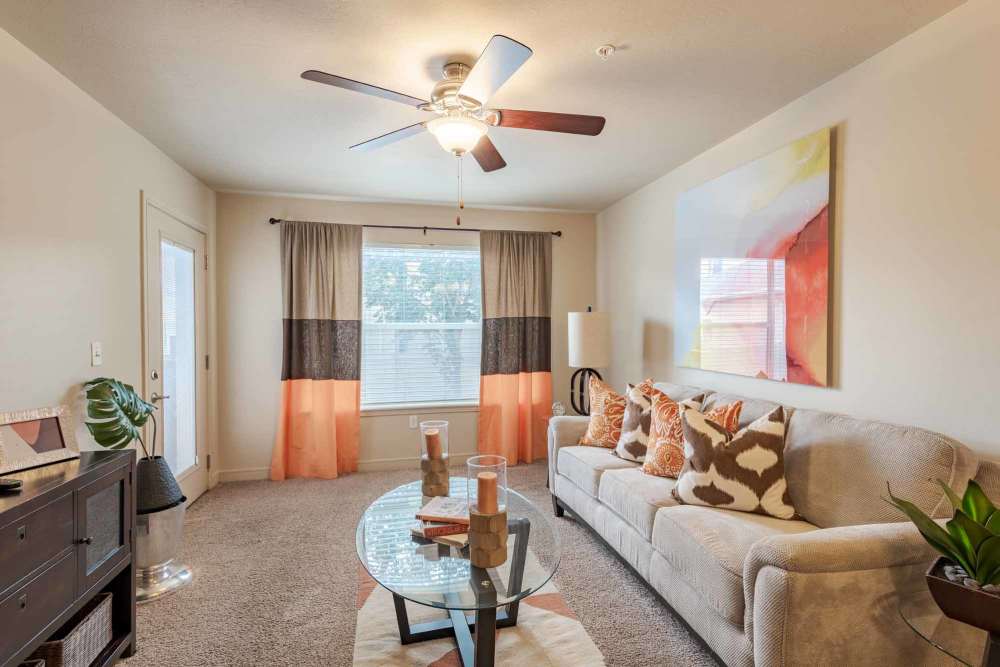 A cozy living room featuring a couch, coffee table, and a ceiling fan overhead at Meadowbrook Station Apartments in Salt Lake City, Utah