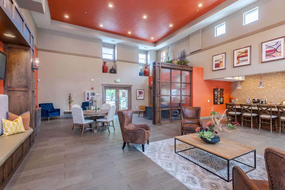 Lobby of a park at the edge of town, featuring seating areas and large windows overlooking the greenery outside at Meadowbrook Station Apartments in Salt Lake City, Utah