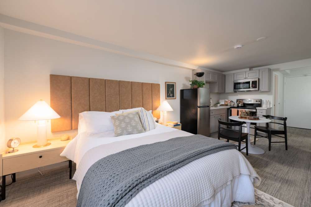 Furnished model apartment home with stainless steel appliances and queen size bed with headboard at Thea Apartments in Tacoma, Washington.
