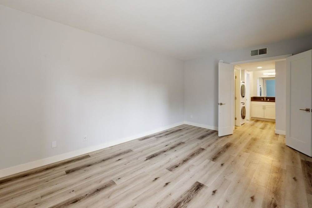 Open layout room with wooden flooring  connecting to washer and dryer at The Indie Glendale Collection in Glendale, California