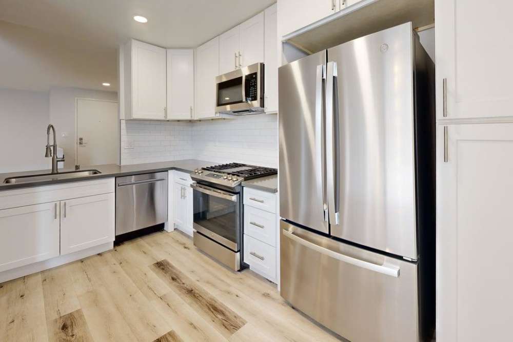 The kitchen with stainless steel appliances, granite countertops and white cabinetry at The Indie Glendale Collection in Glendale, California