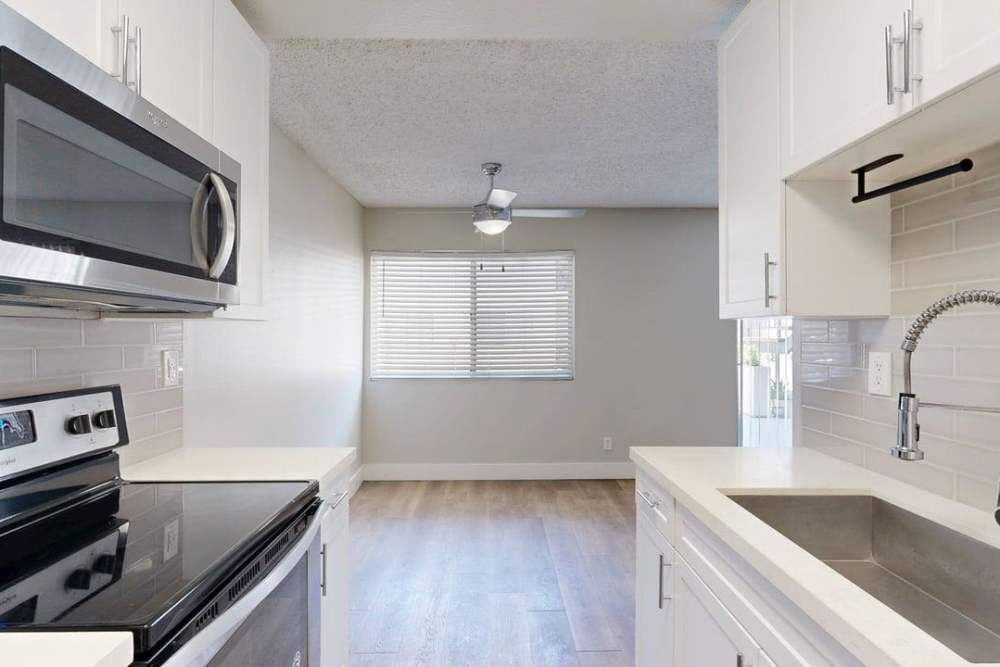 Kitchen with a range with a stainless-steel microwave , sink  and direct access to patio at The Indie Glendale Collection in Glendale, California