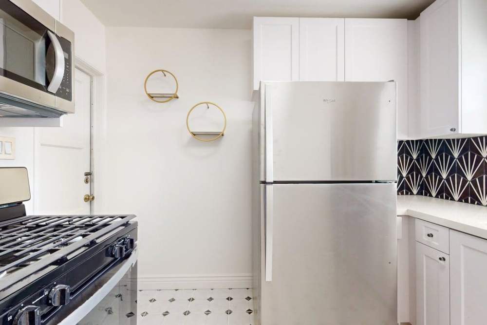 kitchen with steel appliances and white cabinets at The Indie Glendale Collection in Glendale, California