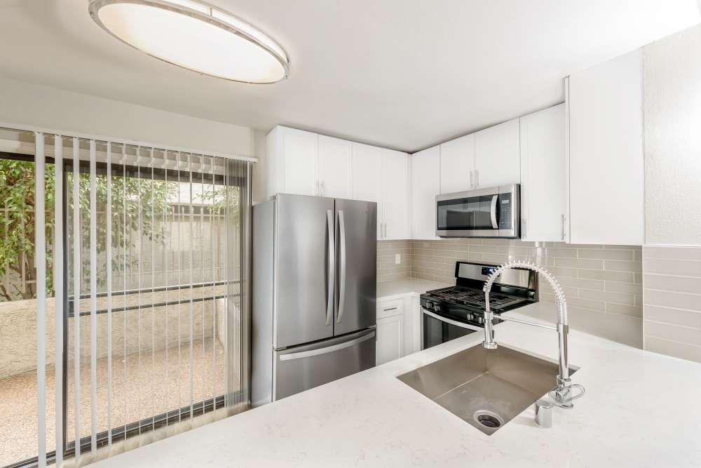 Kitchen with modern steel appliances showing attached patio at The Indie Glendale Collection in Glendale, California
