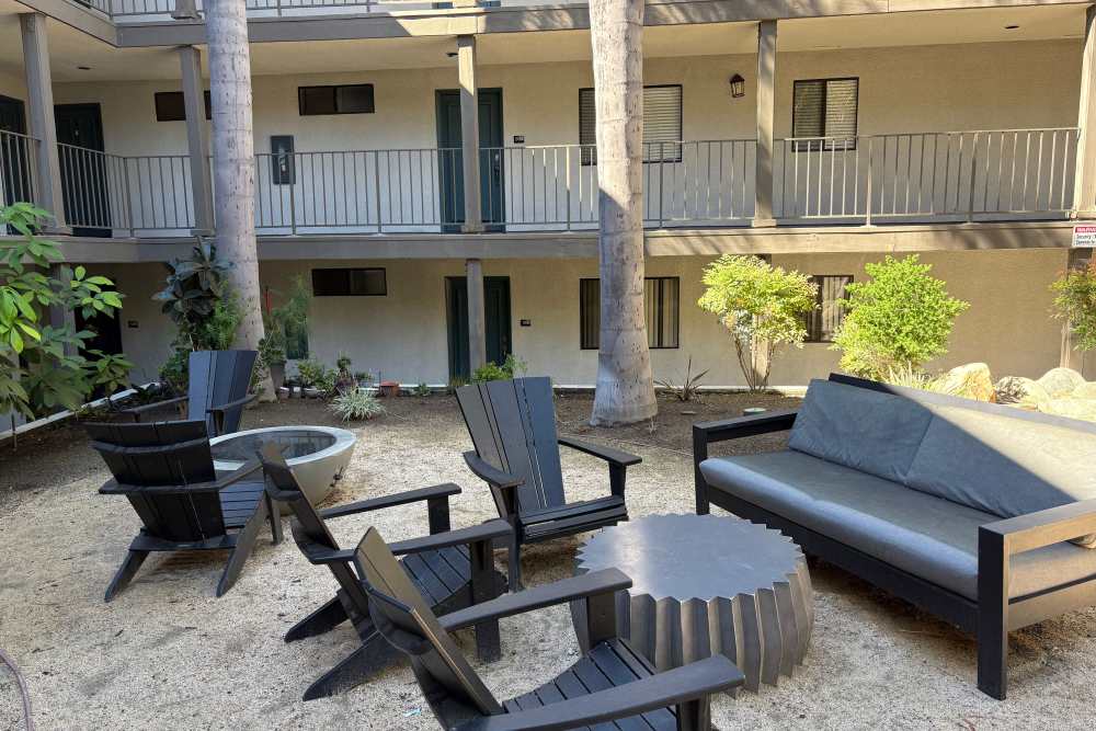 Showing wooden sofa and chairs seating inside community, surrounded with houses and trees at The Indie Glendale Collection in Glendale, California