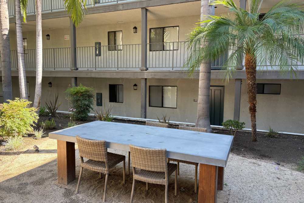 Showing stone dining with chairs inside community, surrounded with houses and trees at The Indie Glendale Collection in Glendale, California