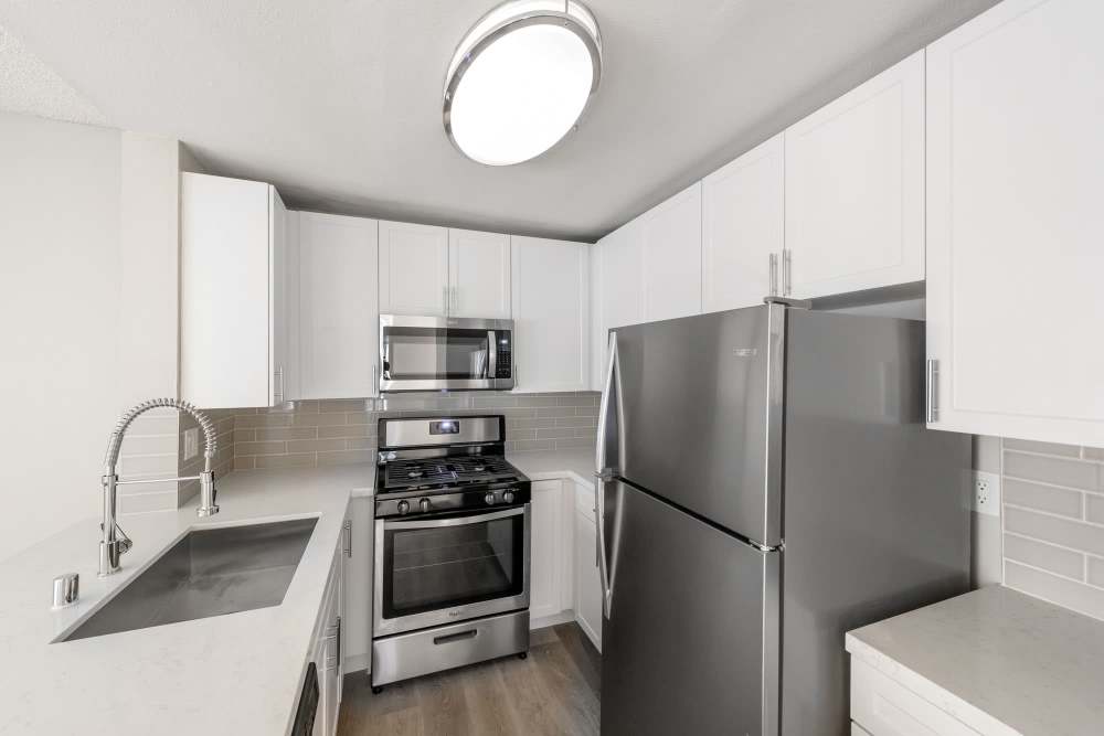 Fully-equipped kitchen with stainless steel appliances and passthrough island with ceiling lights at The Indie Glendale Collection in Glendale, California