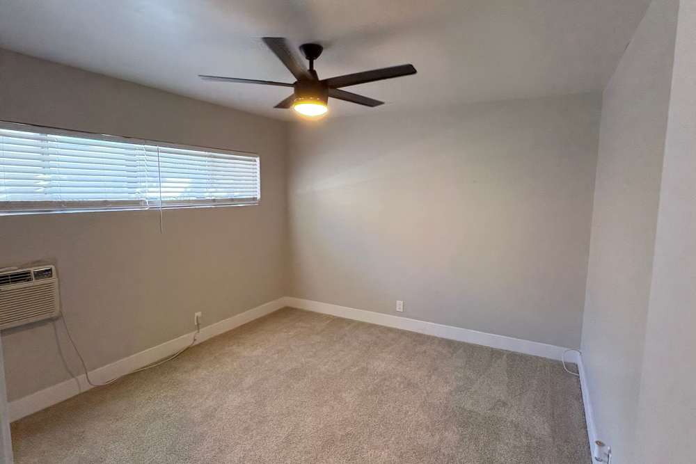 Well-lit bedroom with AC, ceiling fan, large window, and carpet flooring at The Indie Glendale Collection in Glendale, California