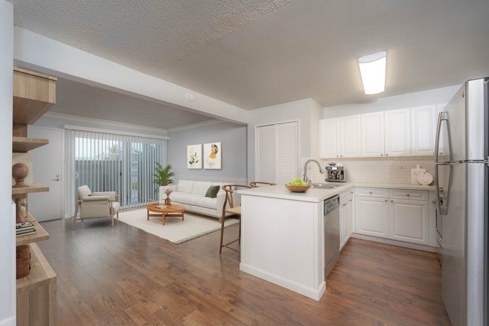 Open kitchen with white cabinets and living space at Breakwater Apartments in Santa Cruz, California