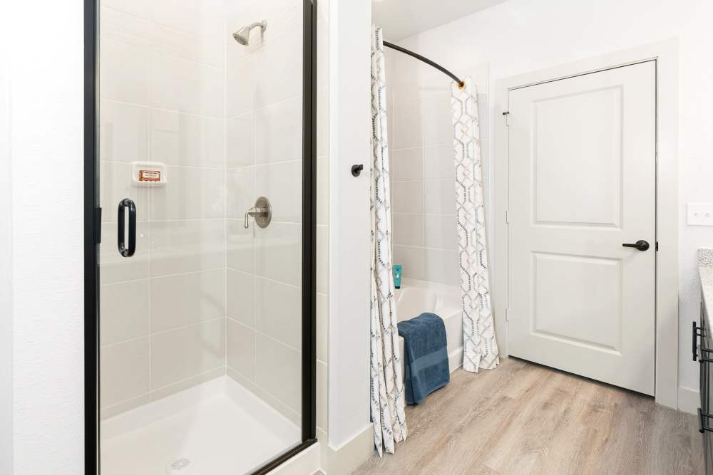 Bathroom with glass shower and tub at The Heyward Apartments in Corinth, Texas.