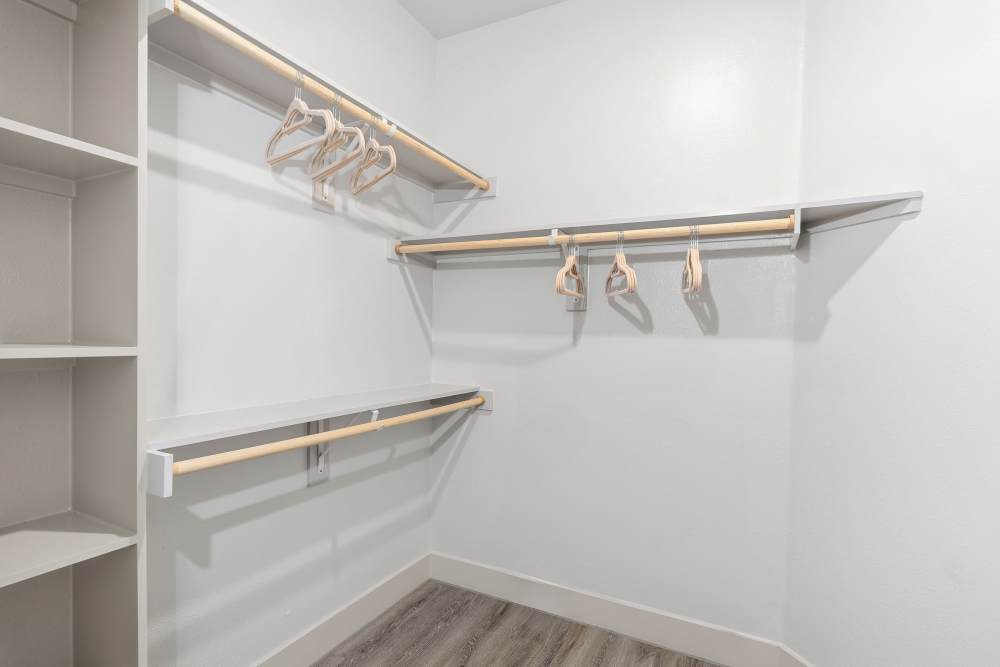 Walk-in closet with shelving and hanging rods at The Heyward Apartments in Corinth, Texas.