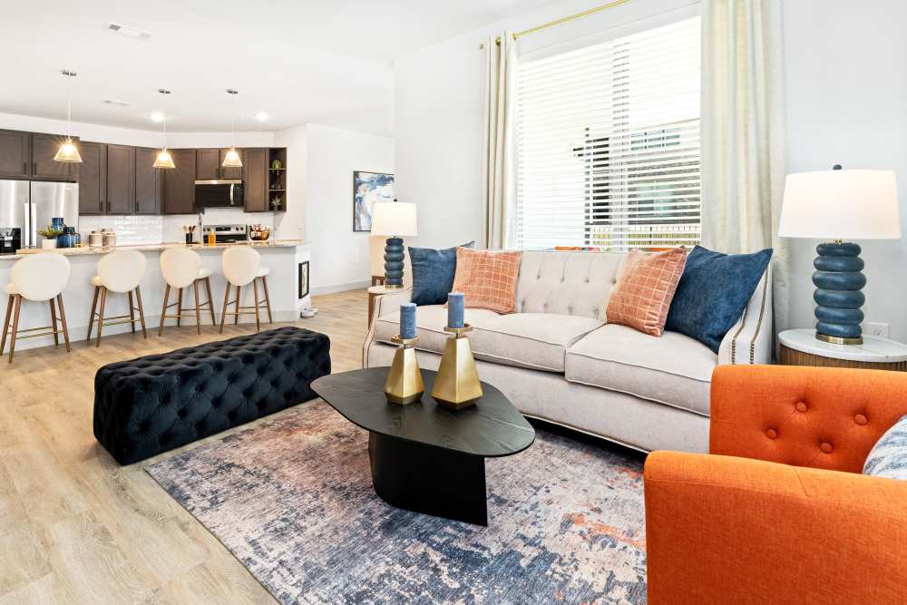 Living room with stylish furniture and open kitchen at The Heyward Apartments in Corinth, Texas.