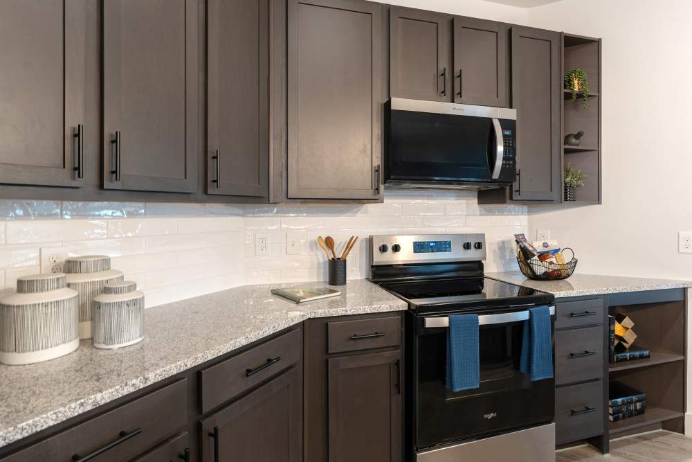 Kitchen with dark cabinets and stainless steel appliances at The Heyward Apartments in Corinth, Texas.