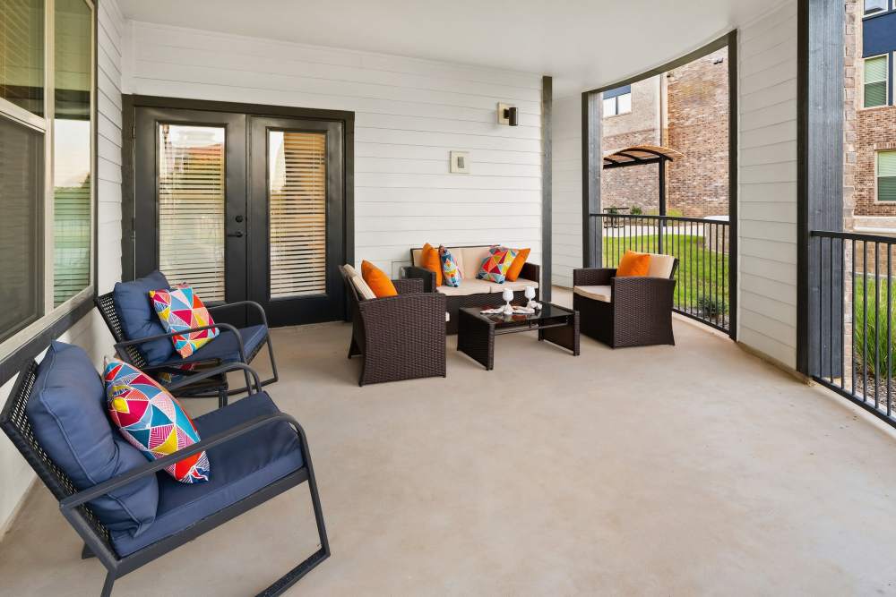 Covered patio with outdoor seating at The Heyward Apartments in Corinth, Texas.