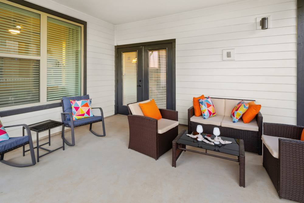 Covered patio with colorful cushions at The Heyward Apartments in Corinth, Texas.