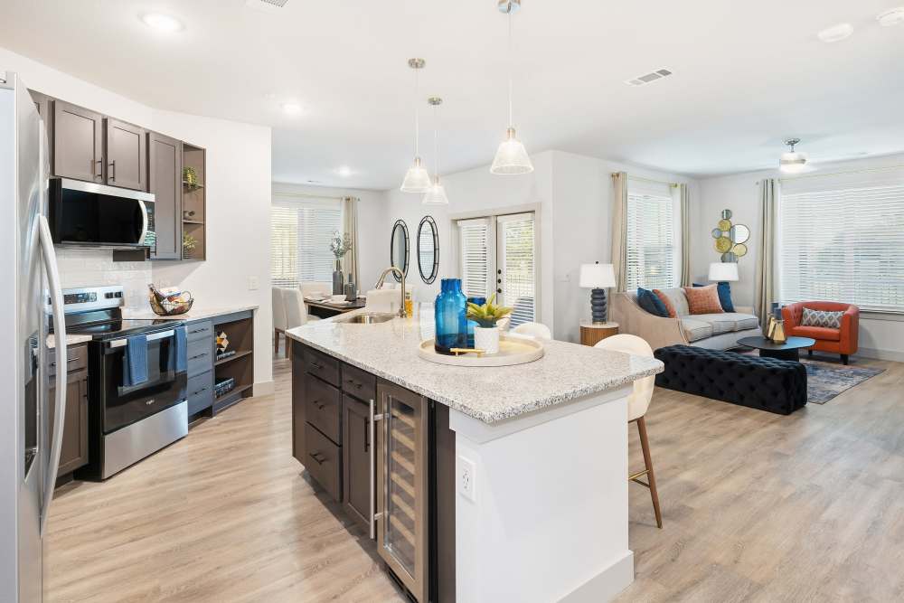 Open kitchen and living space with wood flooring at The Heyward Apartments in Corinth, Texas.