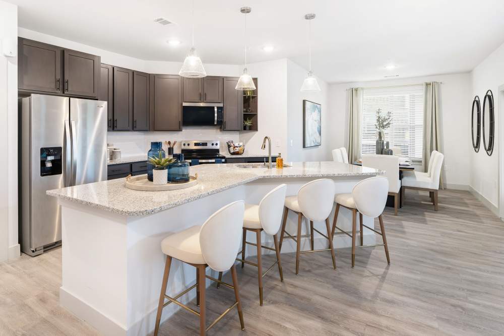 Kitchen and dining area with open layout at The Heyward Apartments in Corinth, Texas.