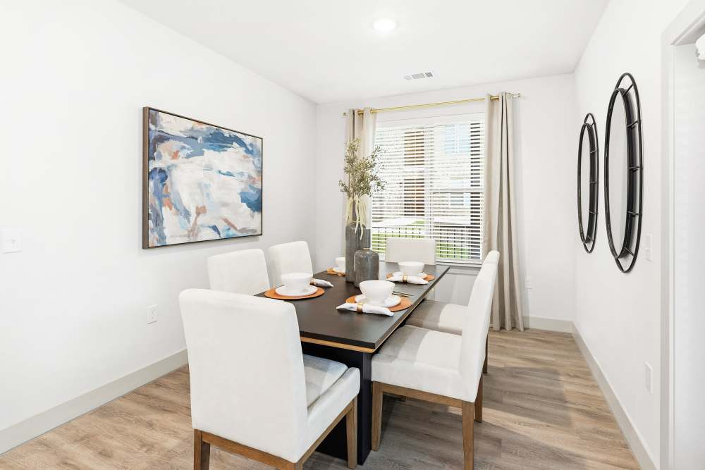 Dining room with six chairs and wall art at The Heyward Apartments in Corinth, Texas.