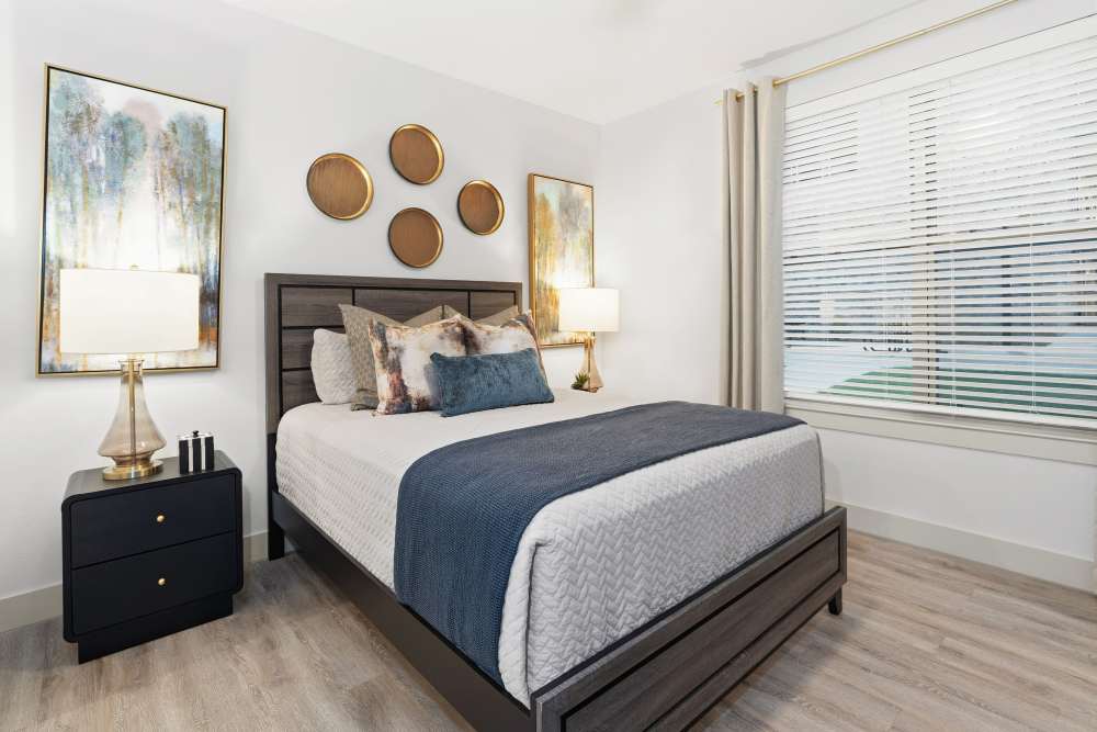 Bedroom with dark wood bed and wall art at The Heyward Apartments in Corinth, Texas.