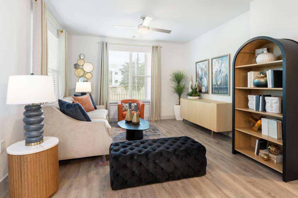 Living room with modern furniture and bookshelf at The Heyward Apartments in Corinth, Texas.