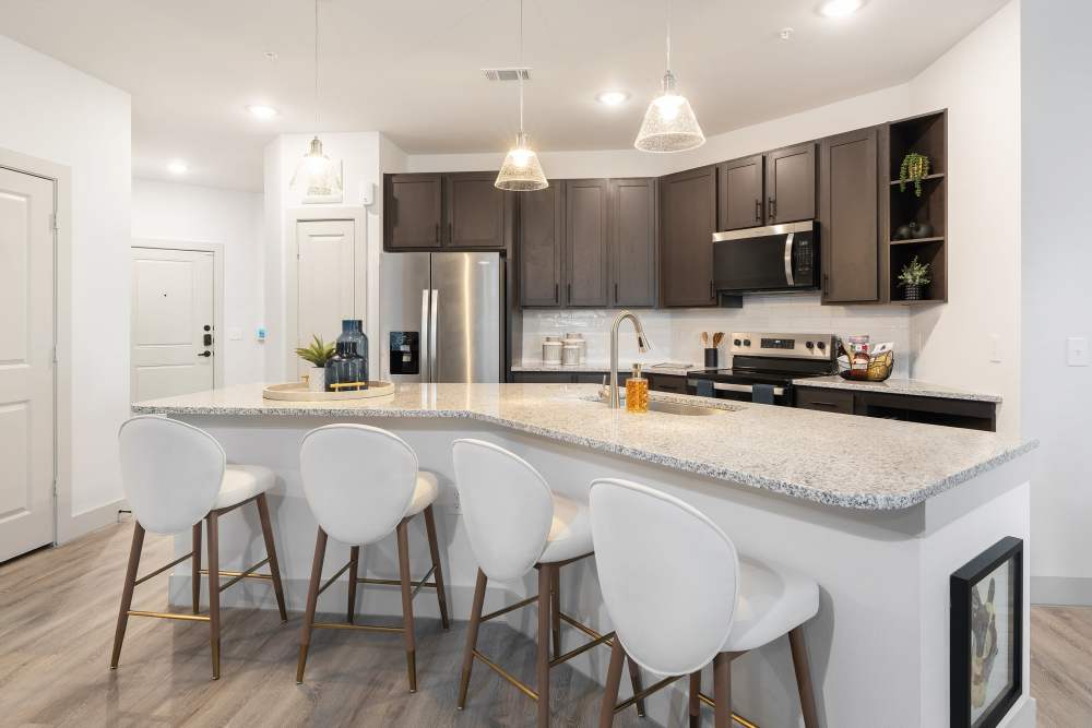 Kitchen with granite island and pendant lights at The Heyward Apartments in Corinth, Texas.