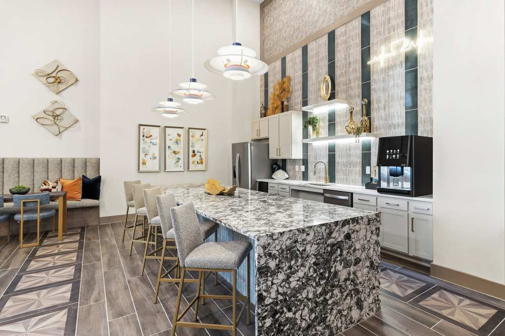 Clubhouse kitchen with marble island and pendant lights at The Heyward Apartments in Corinth, Texas.